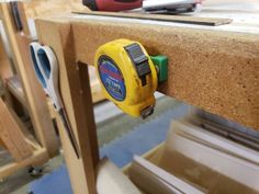 a yellow tape dispenser sitting on top of a wooden table next to tools