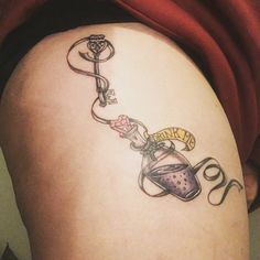 a woman's thigh with a tattoo on it that has a bottle and key attached to it