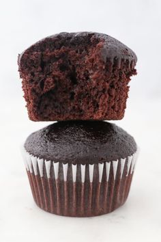 two chocolate cupcakes stacked on top of each other with one bite taken out