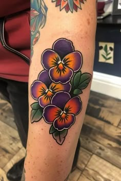 a person with a tattoo on their arm that has three flowers painted on the side