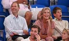 a woman talking on a cell phone while sitting next to two men in the stands