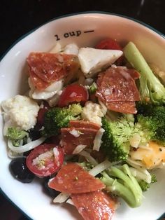 a white bowl filled with broccoli, cauliflower and other food items