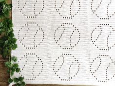 a white crocheted blanket sitting on top of a wooden table next to a plant