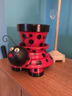 a red and black lady bug sitting on top of a wooden dresser next to a lamp