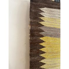 a brown and yellow rug hanging on the wall next to a white wall with a pair of scissors in it