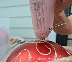 someone is decorating a red ornament with gold glitters on it's side