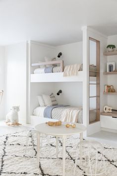 two bunk beds in a room with white walls and flooring, one on top of the