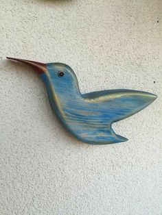 a wooden bird hanging on the side of a wall