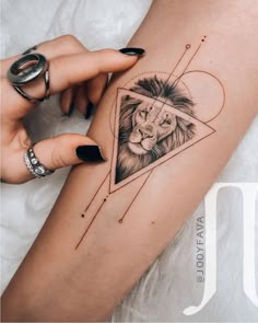 a woman's arm with a lion and triangle tattoo on the left side of her leg