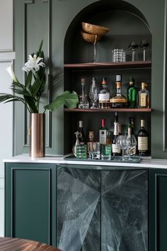 the bar is full of liquor bottles and glasses on it's shelves, along with a potted plant