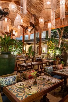 an outdoor dining area with tables, chairs and chandeliers hanging from the ceiling