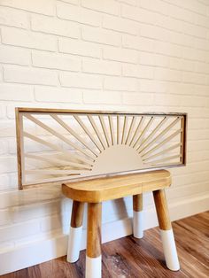 a wooden bench sitting on top of a hard wood floor next to a white brick wall