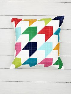 a multicolored pillow sitting on top of a white wooden floor next to a wall