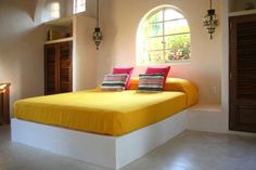 a bed with yellow sheets and colorful pillows