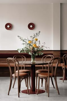 a dining room table with chairs and flowers on it