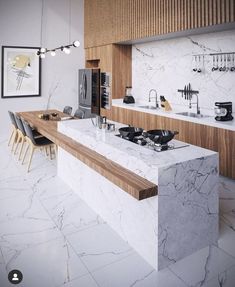 a modern kitchen with marble counter tops and wooden cabinetry, along with black chairs