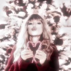 a woman holding a heart shaped lollipop in front of a christmas tree