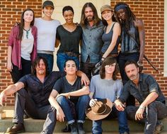 a group of people sitting on the steps posing for a photo with one person holding a hat