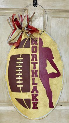 a football ornament hanging on a door with a red and yellow ribbon around it