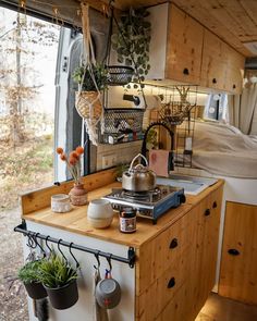 an rv kitchen with pots and pans hanging from the ceiling, next to a bed