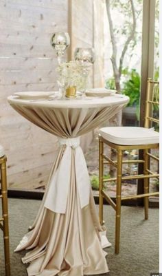 the table is set up with gold chairs and white linen draped over it, along with an elegant centerpiece