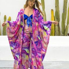 Introducing our fabulous long silky and gorgeous Blossom Kimono - the epitome of versatility! Whether you're hitting the marina scene or painting the town fuchsia at the coolest music festival, this beauty's got you covered. The print gracing this garment is a stunning abstract flower design, from our special partnership with the talented artist Mari Munet, who was stirred by the cherished tokens of a summer romance. Wear it over the Loto Maillot, with the coordinated Blossom Pant or just to surround yourself in self-love indulgence over your trusted jeans with heal slingbacks. Embrace the chic, relaxed vibes, and let your style bloom effortlessly. One Size Pink Kimono For Summer, Spring Festival Kimono With Vibrant Print, Vibrant Spring Kimono With Vibrant Print, Pink Beachwear Kimono For Spring, Summer Kimono With Vibrant Print, Pink Kimono For Beach Season Cover-up, One Size Pink Kimono For Festival, Pink Bohemian Summer Kimono, Summer Silk Kimono Flowy Fit