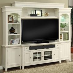 a white entertainment center with a large flat screen tv on it's side shelf