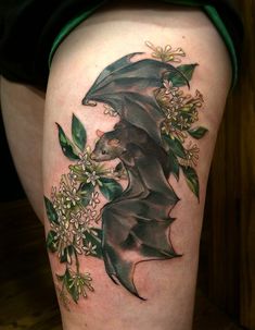 a woman's thigh with a bat and flowers on it