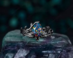 a ring with an opal colored stone in the center on top of a rock