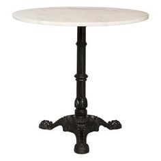 a white marble table with black metal legs and an ornate design on the base, against a white background