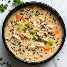 a black bowl filled with chicken and rice soup on top of a white countertop