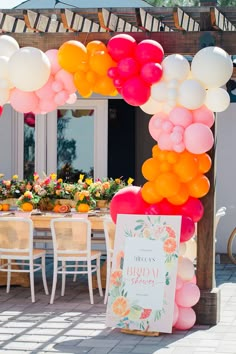 an outdoor party with balloons and flowers on the table