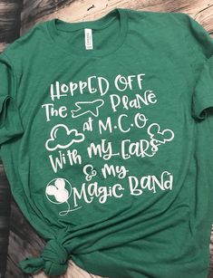 a green t - shirt with white writing on it that says, helped off the stage at m & c with my ears and my magic band