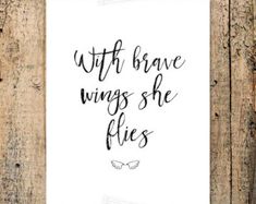 a white sign that says, with brave wings she flies