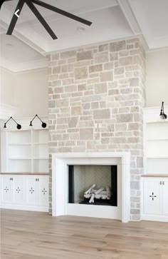 an empty living room with white cabinets and a brick fireplace in the center, surrounded by wood flooring