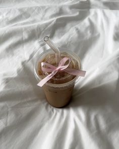 there is a cup of coffee with a pink bow on the lid and some straws in it