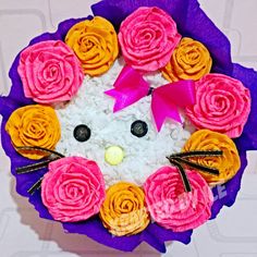 a bouquet of flowers made to look like a hello kitty face with pink, yellow and orange roses