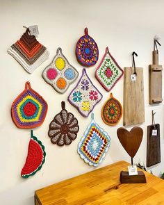 there are many crocheted items hanging on the wall next to a wooden table