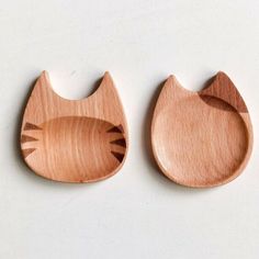 two wooden cat shaped dishes on a white surface