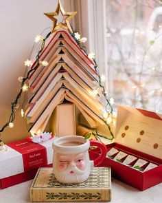 a small christmas tree sitting on top of a box next to a cup and book