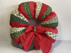 a red and green christmas wreath on a white background with polka dots, bows and snowflakes