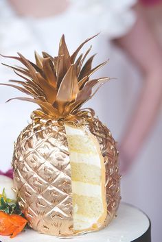 a pineapple shaped cake with a slice cut out on the side, sitting on top of a table