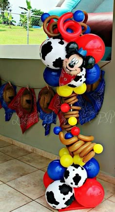 a mickey mouse balloon sculpture on display in a room with tile flooring and walls