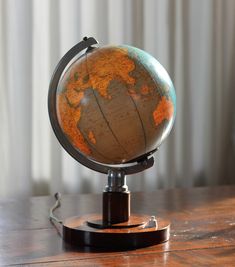 an old globe sits on a wooden table