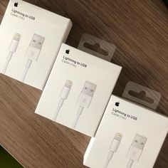 three apple lightning usb cables sitting on top of a wooden table