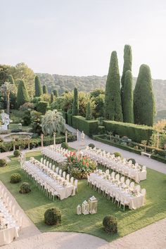 an outdoor wedding setup with white linens and tables set up in the middle of a garden