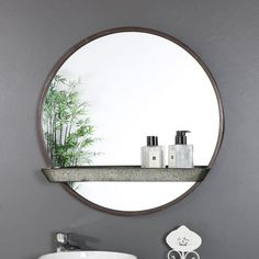 a bathroom sink sitting under a round mirror