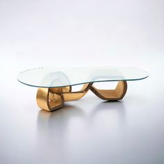 a glass and gold coffee table with an oval shaped design on the top, in front of a white background