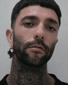 a man with tattoos and piercings on his neck