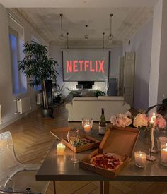 a living room filled with lots of furniture next to a table topped with pizza and candles